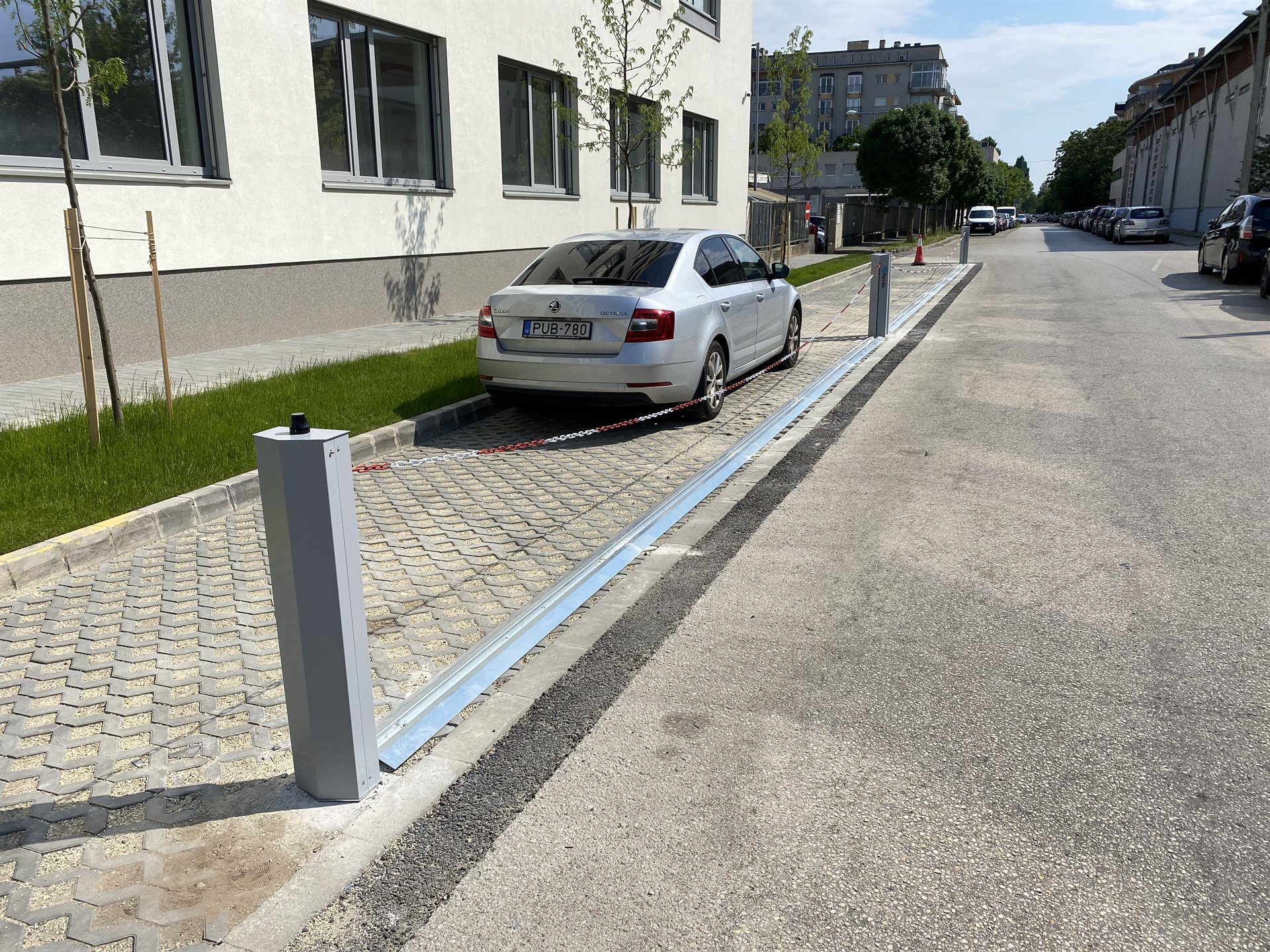 Kettenabsenker sperrt mit gespannter Kette eine ganze Stellplatzreihe vor einem Geb&auml;ude